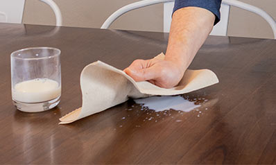using bravo towel to clean a spill on a dining room table
